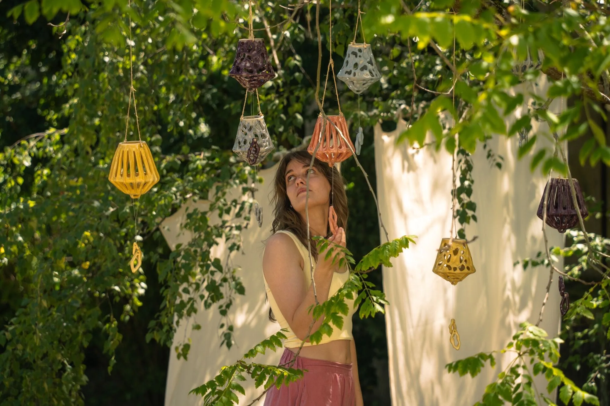 Photophores en céramique suspendus dans les branches d'un arbre