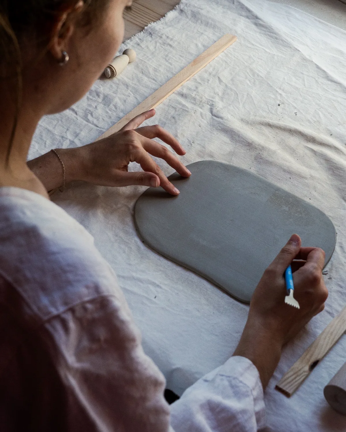 Mains façonnant une plaque d'argile à l'atelier